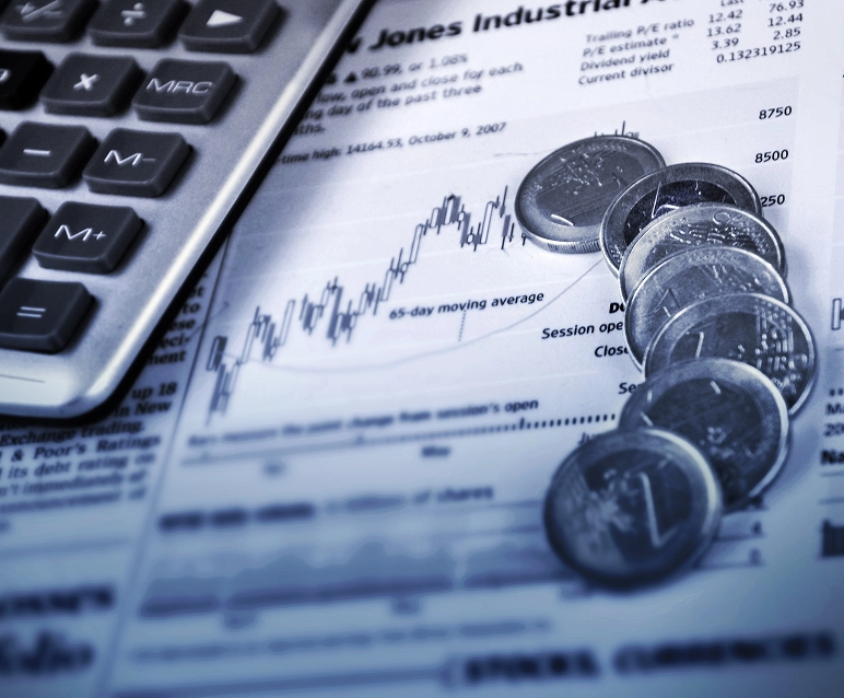 Calculator and coins on financial newspaper graph.